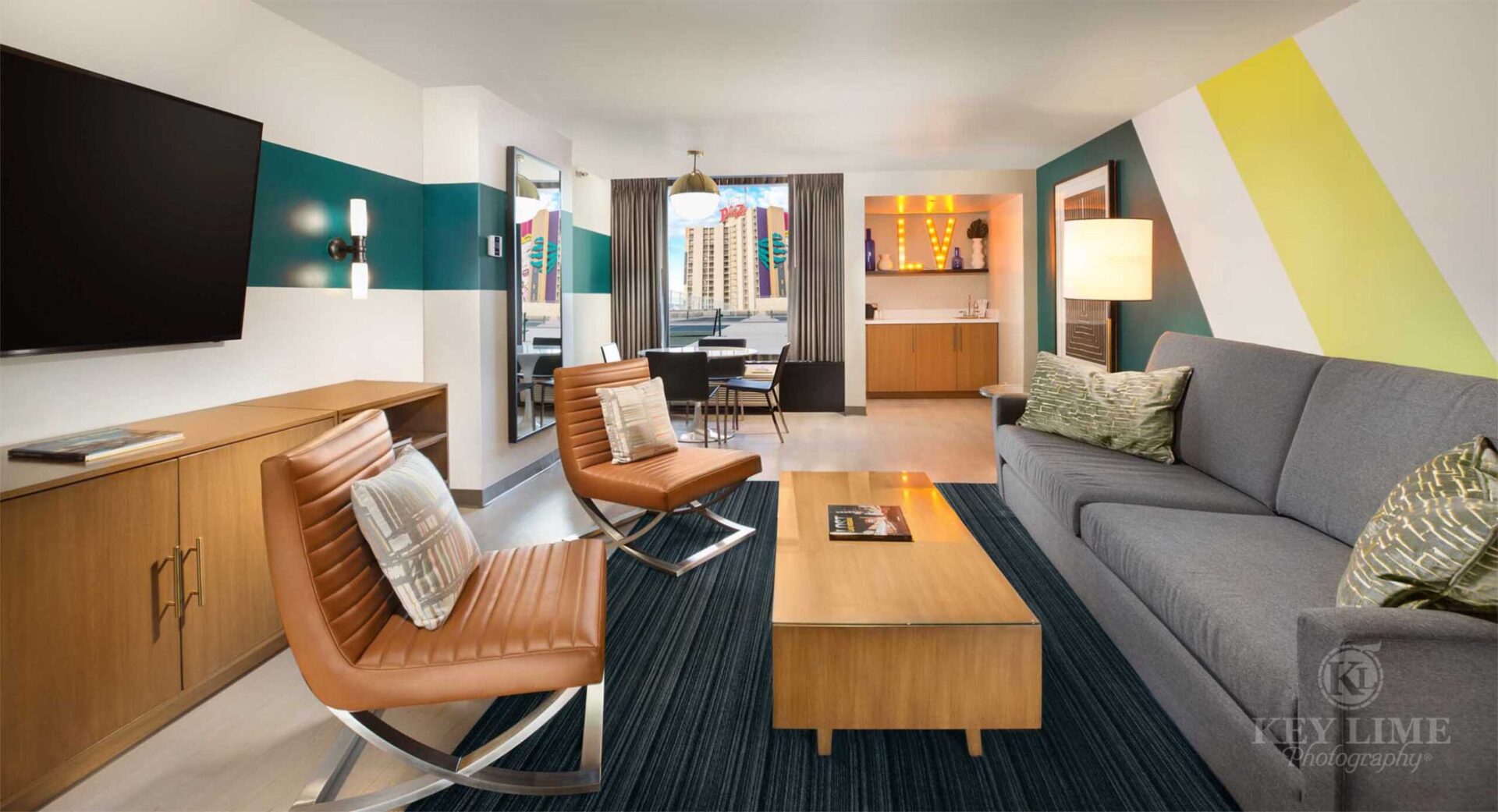 Pool suite inside a Las Vegas hotel. Building photographer image. Bachelor pad with gray sofa and tan, leather chairs.