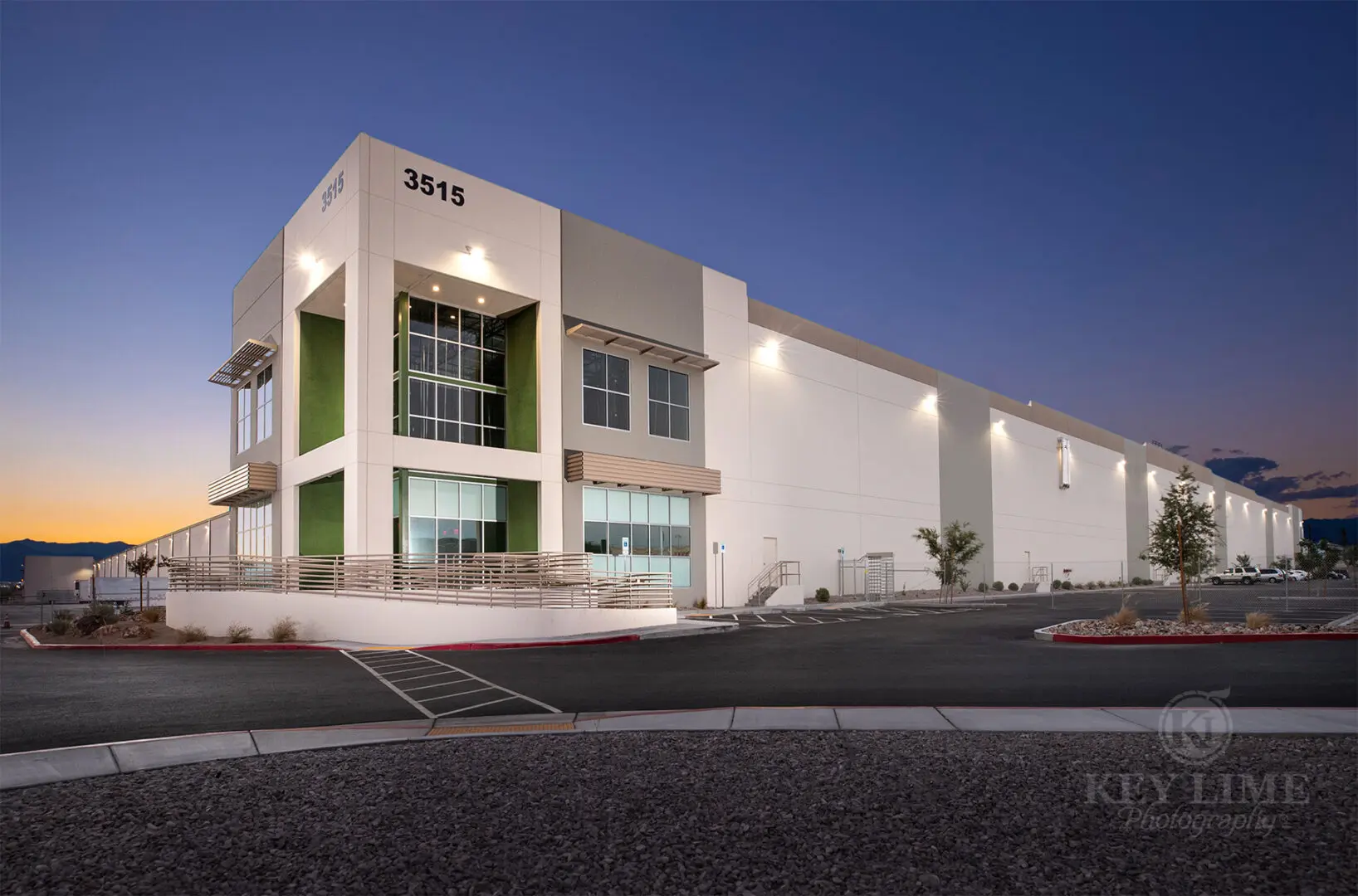 Commercial architecture photographer image of white and green warehouse against a blue twilight sky..