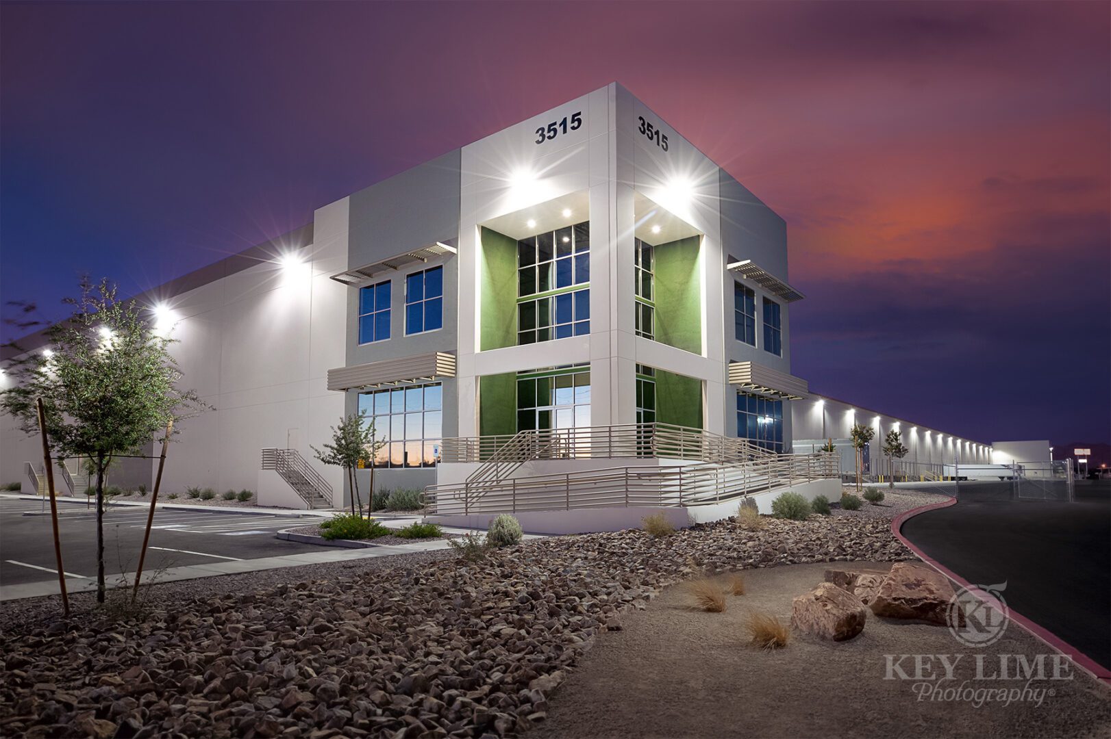 Commercial architecture photographer image of white and green warehouse against a magenta sunset.