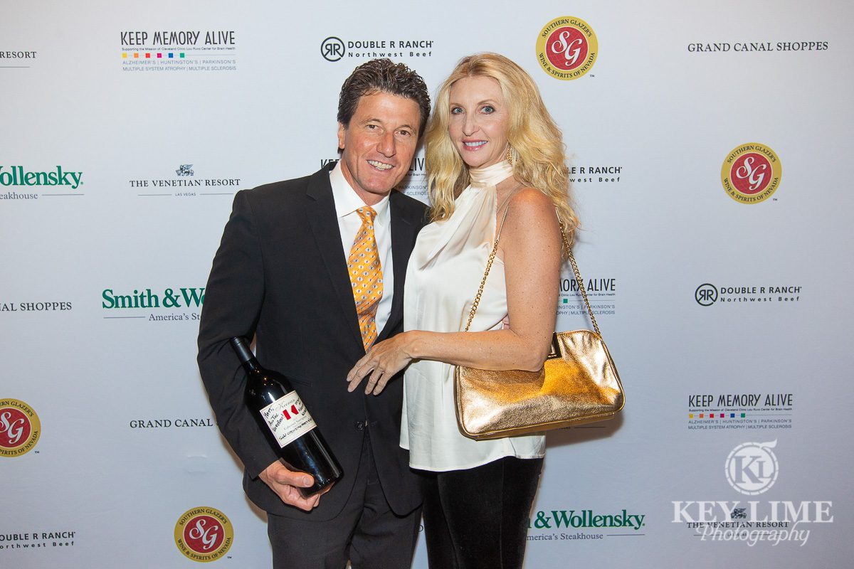 Red carpet entrance of the grand opening of Smith & Wollensky Las Vegas. Man and woman stand smiling with gift bottle.