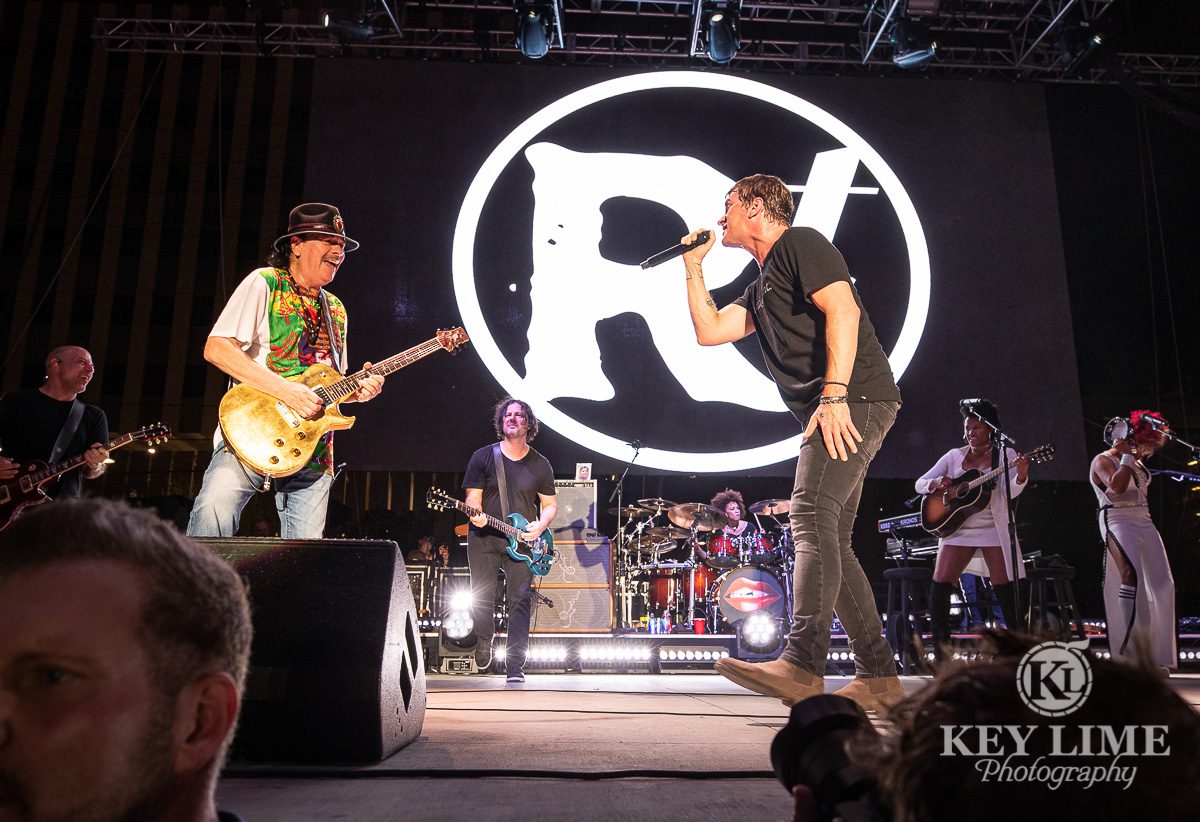 Event photography of Rob Thomas being joined by Santana for performance of Smooth, artists perfomring and smiling at each other