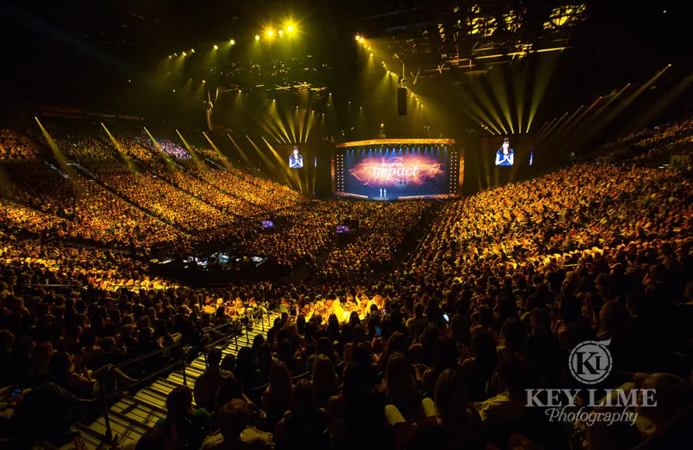 A arena full of an audience with the projection saying "Make an Impact"