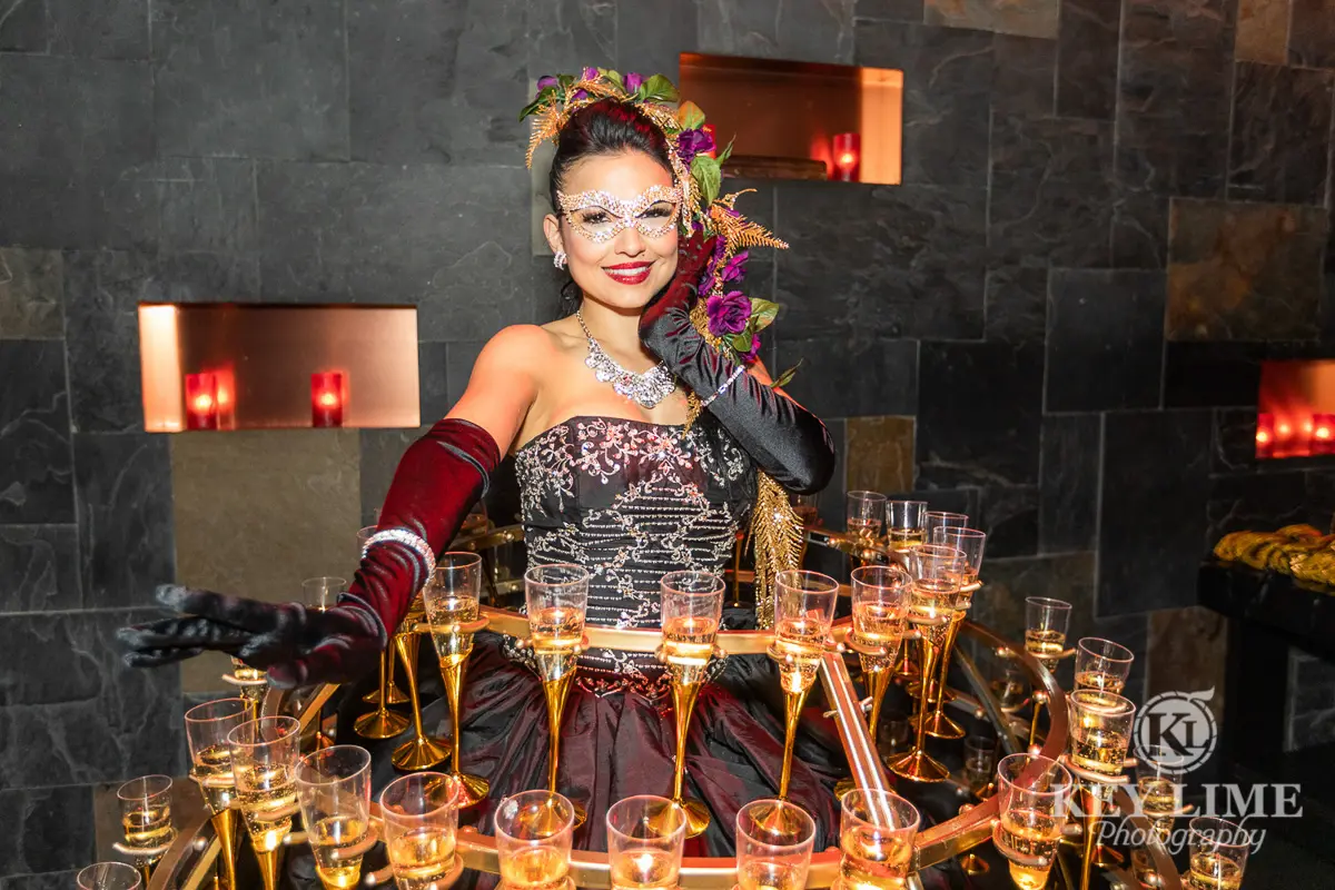 Las Vegas photographer image of model smiling while supporting a dress that serves champagne flutes during an event.