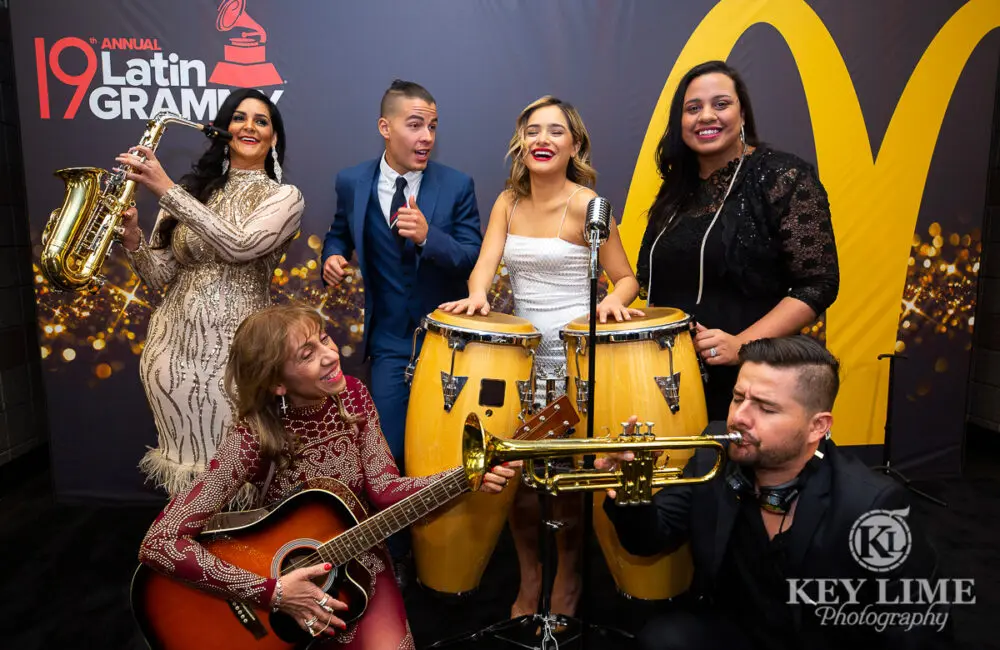 An image from the 19th annual Latin Grammy Awards with people playing a guitar, a pair of drums, a saxophone, and a trumpet.